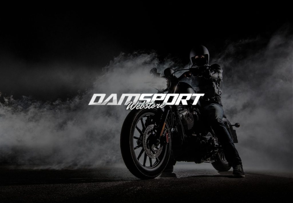 Motocicleta custom negra con humo y piloto equipado, logo Damsport Webstore, tienda de accesorios moto