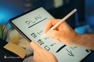 Manos escribiendo un plan de acción con checklist en tablet usando stylus, planificación estratégica SEO digital