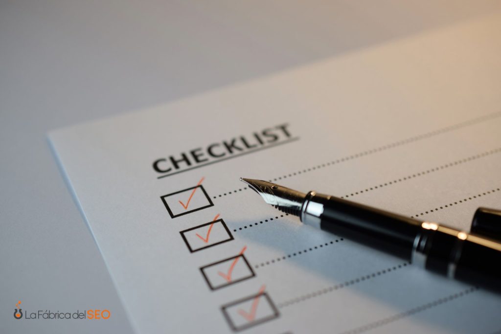 Checklist con casillas marcadas en rojo y bolígrafo de punta fina sobre papel blanco, lista de verificación SEO
