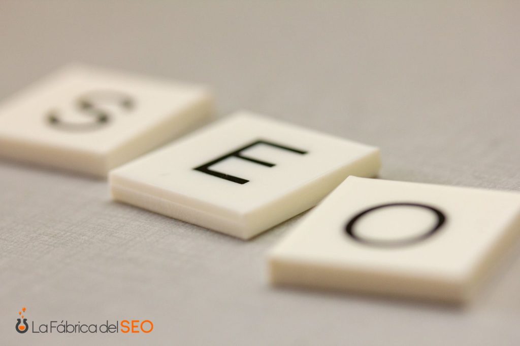 Tres fichas de Scrabble formando la palabra SEO sobre superficie gris, concepto de posicionamiento web