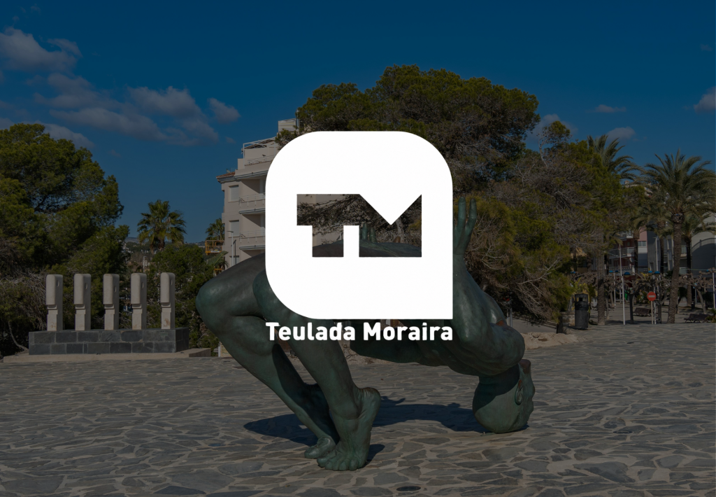 Logotipo oficial de Teulada Moraira sobre escultura de bronce en la plaza costera del municipio valenciano