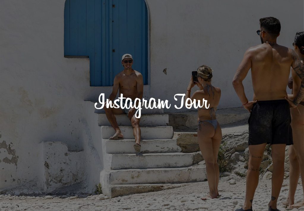 Tour de Instagram en Santorini: grupo de turistas fotografiando en escaleras blancas con puerta azul típica griega