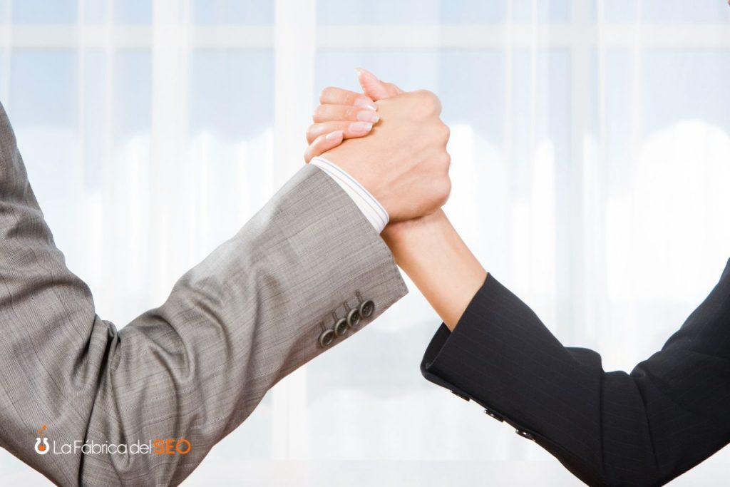 Dos profesionales compitiendo en pulso de brazos con trajes de negocios, simbolizando la competencia empresarial