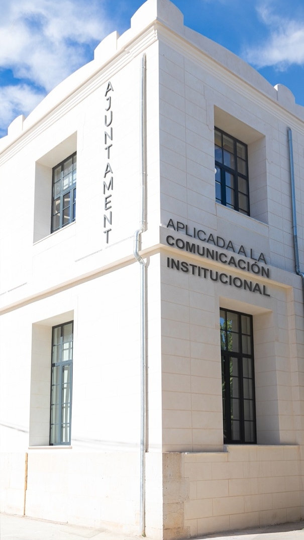 Fachada blanca del Ajuntament con letras sobre comunicación institucional aplicada, cielo azul de fondo