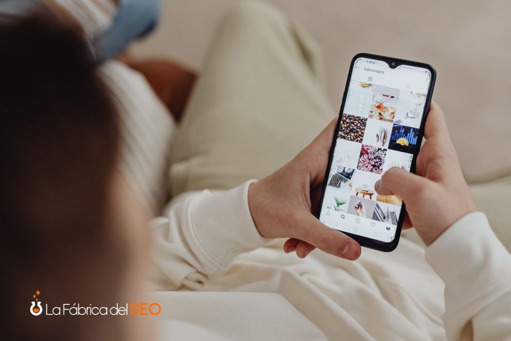 Persona navegando perfil de Instagram en smartphone desde el sofá, explorando contenido visual de restaurantes