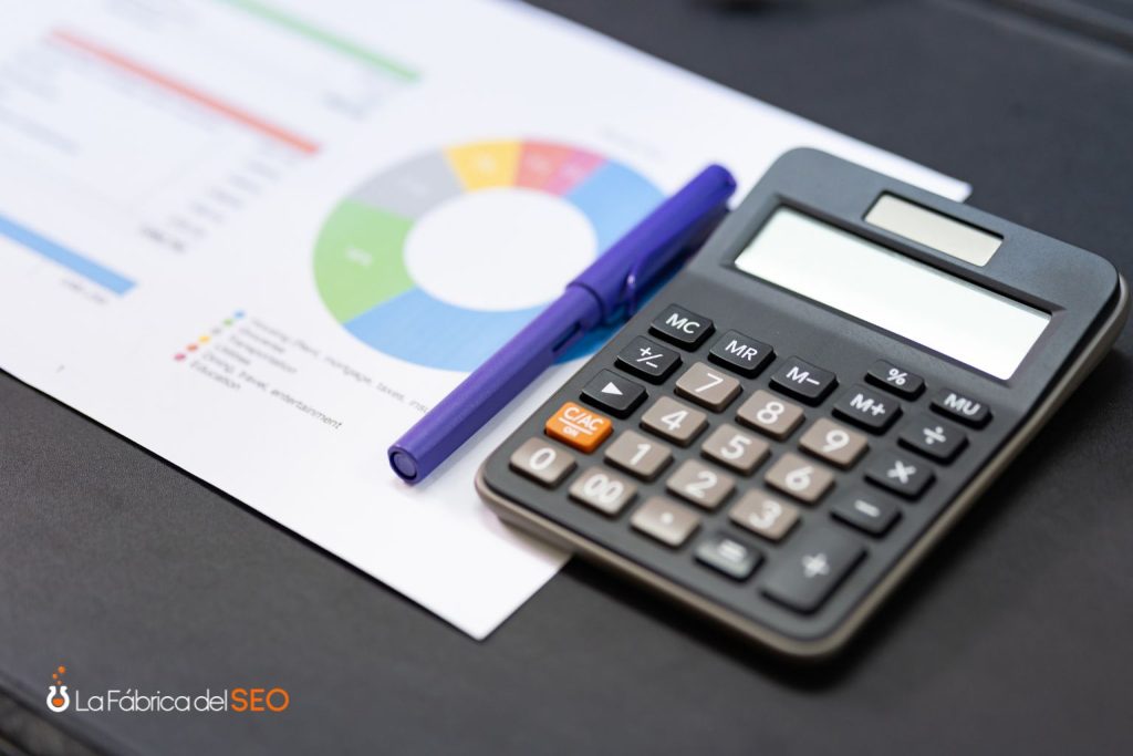 Calculadora negra sobre informe financiero con gráfico circular de colores y bolígrafo azul para presupuesto