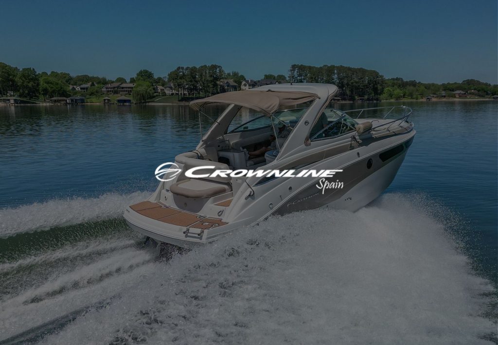 Lancha Crownline Spain navegando a alta velocidad en lago con casas residenciales al fondo
