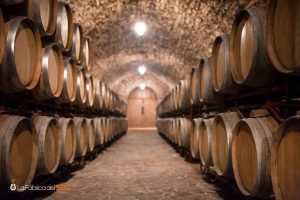 Barrica de roble en bodega subterránea con bóveda de piedra y barricas alineadas para envejecimiento de vino