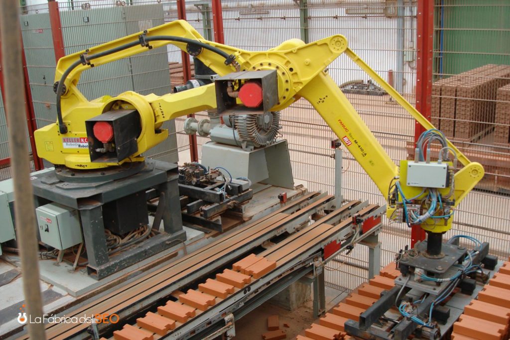 Robot industrial FANUC M-410 amarillo paletizando ladrillos cerámicos en fábrica automatizada