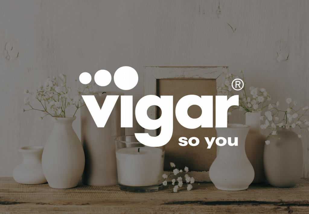Logotipo de Vigar So You en blanco sobre fondo con jarrones cerámicos, flores y vela decorativa estilo nórdico