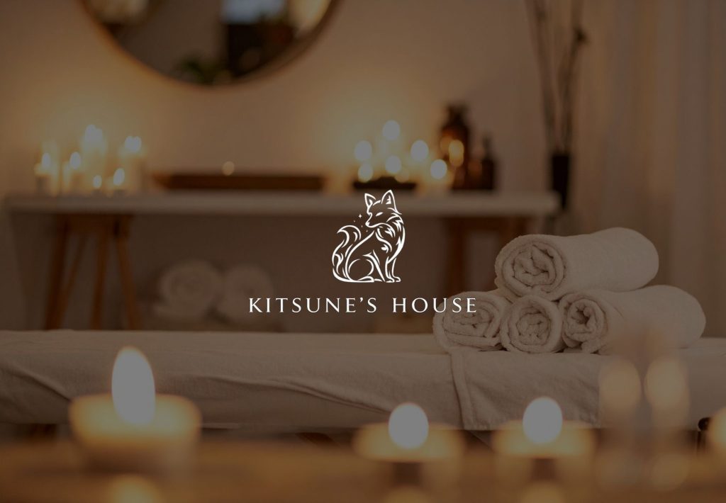 Logo de Kitsune's House con zorro elegante sobre ambiente de spa con velas y toallas enrolladas