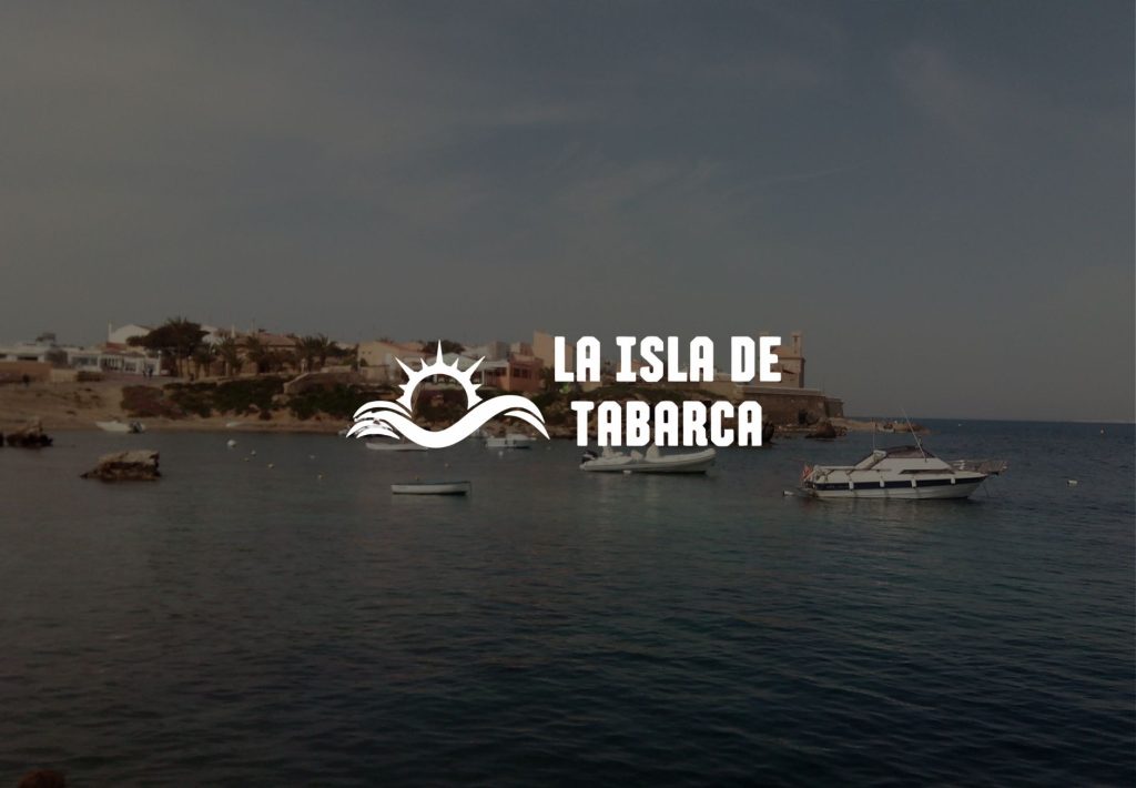 Logo de La Isla de Tabarca con vistas al puerto y barcos fondeados en aguas mediterráneas tranquilas