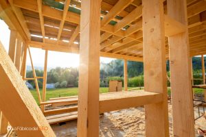 Estructura de madera en construcción con vigas y pilares de madera para almacén, rodeado de naturaleza al atardecer