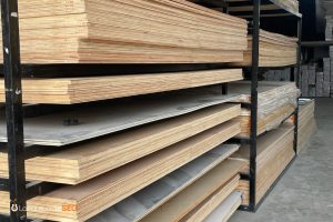 Almacén de madera con estanterías metálicas cargadas de tableros y planchas de madera contrachapada apiladas