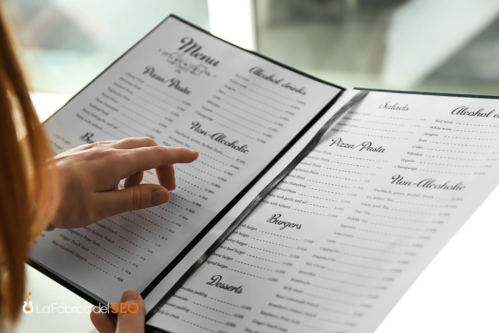 Mujer revisando carta de restaurante con secciones de pizza, pasta, burgers, ensaladas y bebidas alcohólicas y sin alcohol