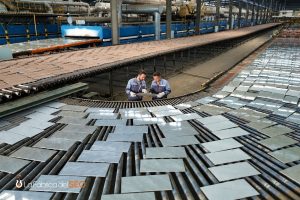 Dos operarios inspeccionando azulejos cerámicos en línea de producción de fábrica de azulejos industrial