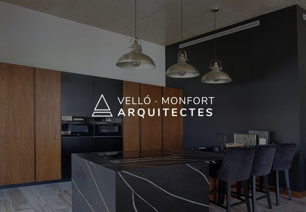Cocina de diseño moderno con isla de mármol negro y armarios de madera, proyecto de Velló Monfort Arquitectes
