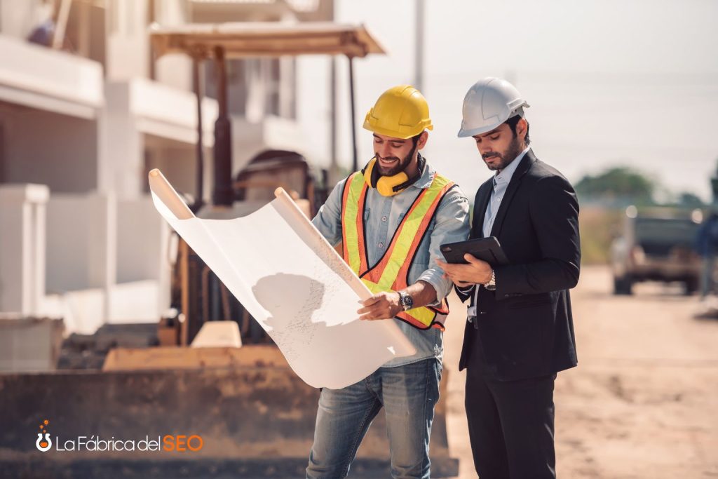 Arquitecto y constructor revisando planos en obra de construcción residencial con casco de seguridad y tablet