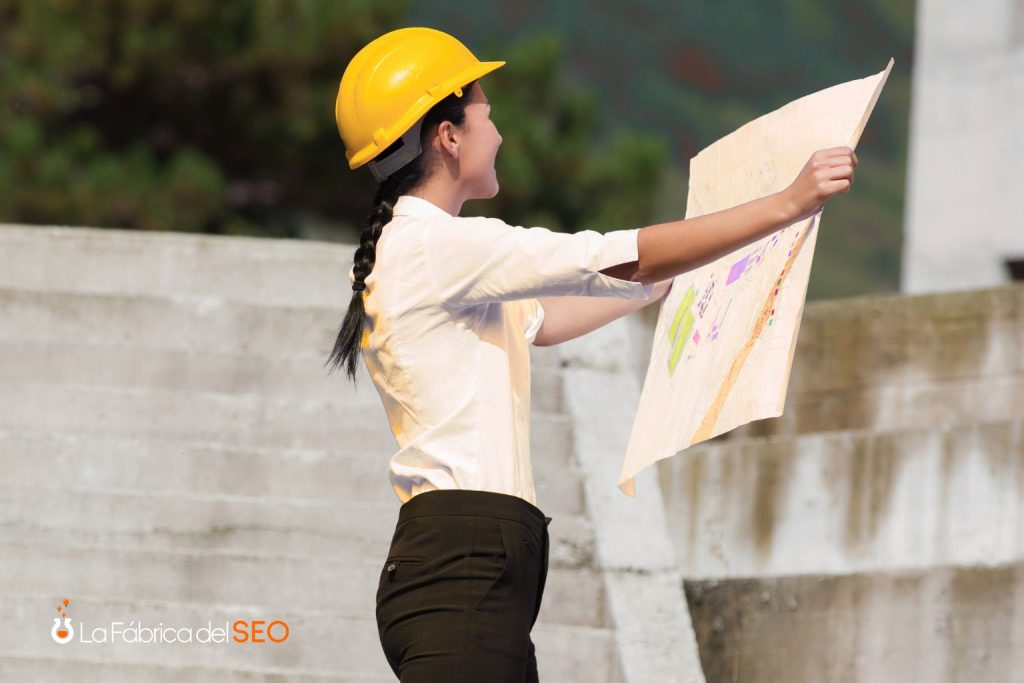 Arquitecta con casco de seguridad amarillo revisando planos en obra de construcción con productos cerámicos