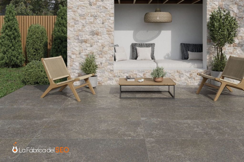 Terraza exterior con cerámica antideslizante gris marrón, sillas de madera y zona lounge con pared de piedra natural