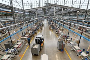 Amplia fábrica industrial moderna con líneas de producción automatizadas, carretilla elevadora y operarios trabajando en nave